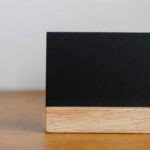 A small blank chalkboard with a wooden base sits on a table, indicating the endless possibilities of what your business name can be.