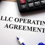 LLC Operating Agreement document with calculator and pen