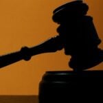 Judge's gavel silhouette on orange background
