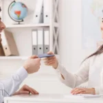 Woman handing E2 business visa to man in office